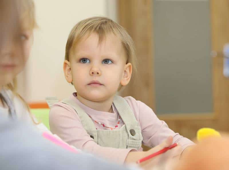 Toddler sits in daycare listening attentively without any flu vaccination side effects.