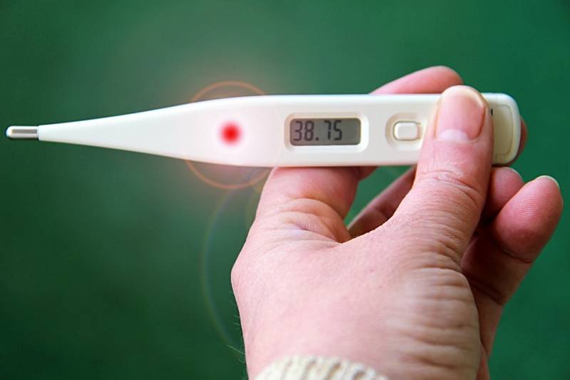 A person holds a digital thermometer a handy addition to a home care first aid kit