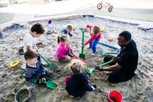 educatior in sandpit with children