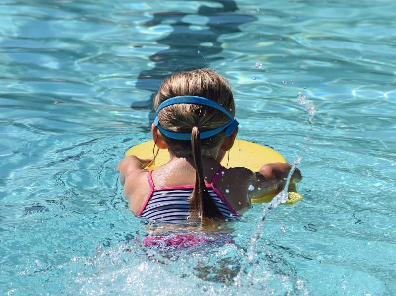A child uses a kickboard in a toddler swimming lessons.
