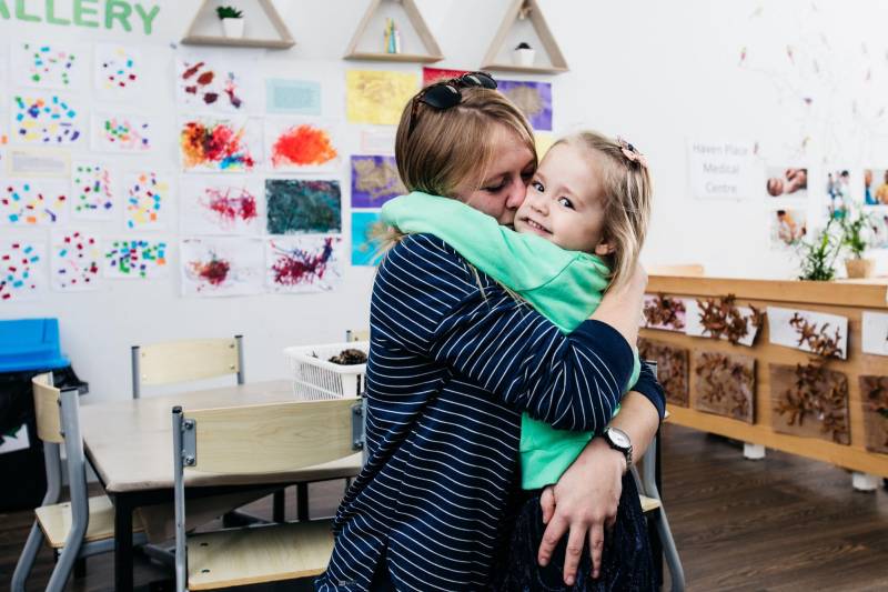 Mum and child hug in a daycare centre where their childcare search is over.