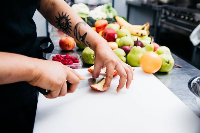 Centre chef cuts up fruit as a healthy snack. Snacks deter kids biting because of hunger.