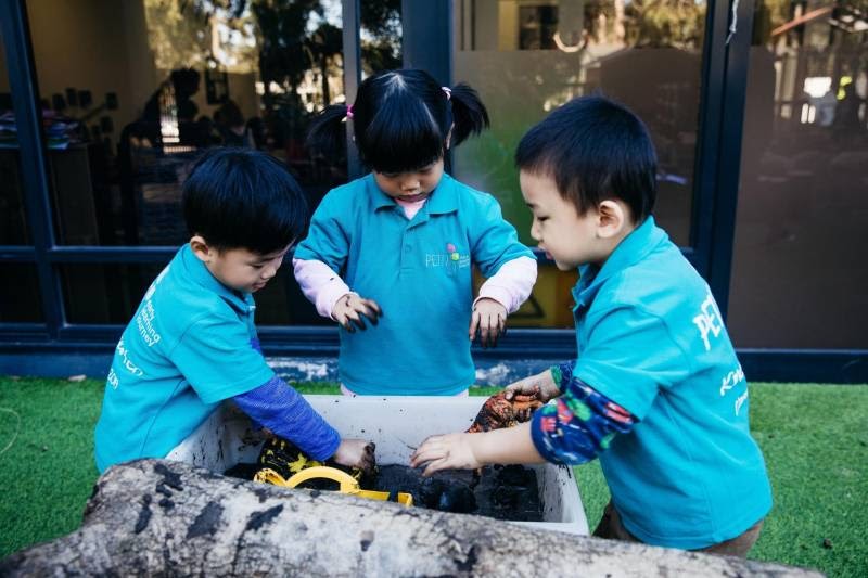 Children have fun in a tub of mud as part of an outdoor play experience.